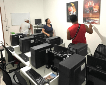 dois homens e uma mulher preparam últimos detalhes do laboratório de informática montado para oferecer os cursos