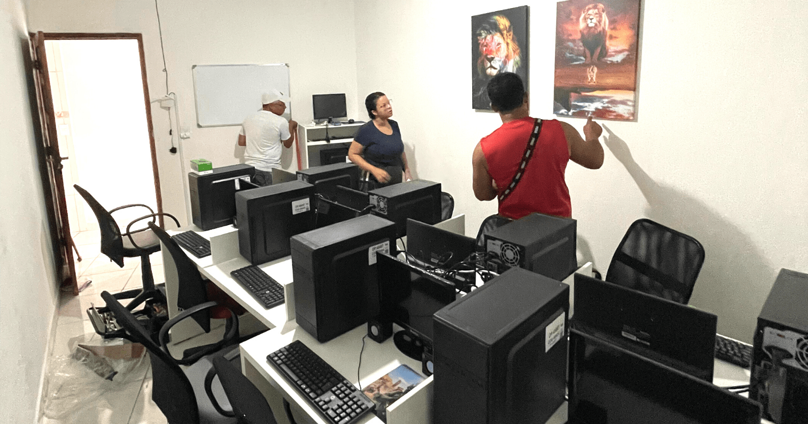 dois homens e uma mulher preparam últimos detalhes do laboratório de informática montado para oferecer os cursos